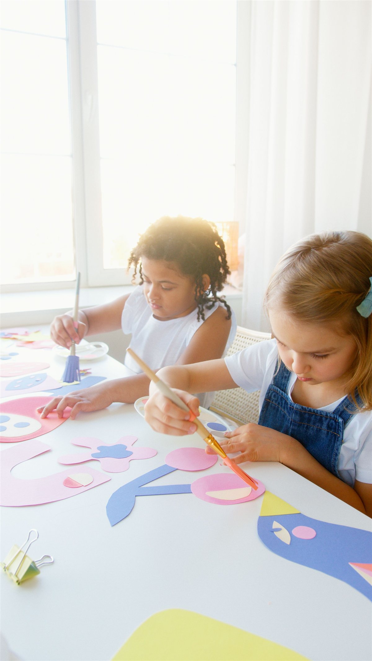 Child creating mixed media artwork using paint, collage and textured materials at SparkPreneurs.